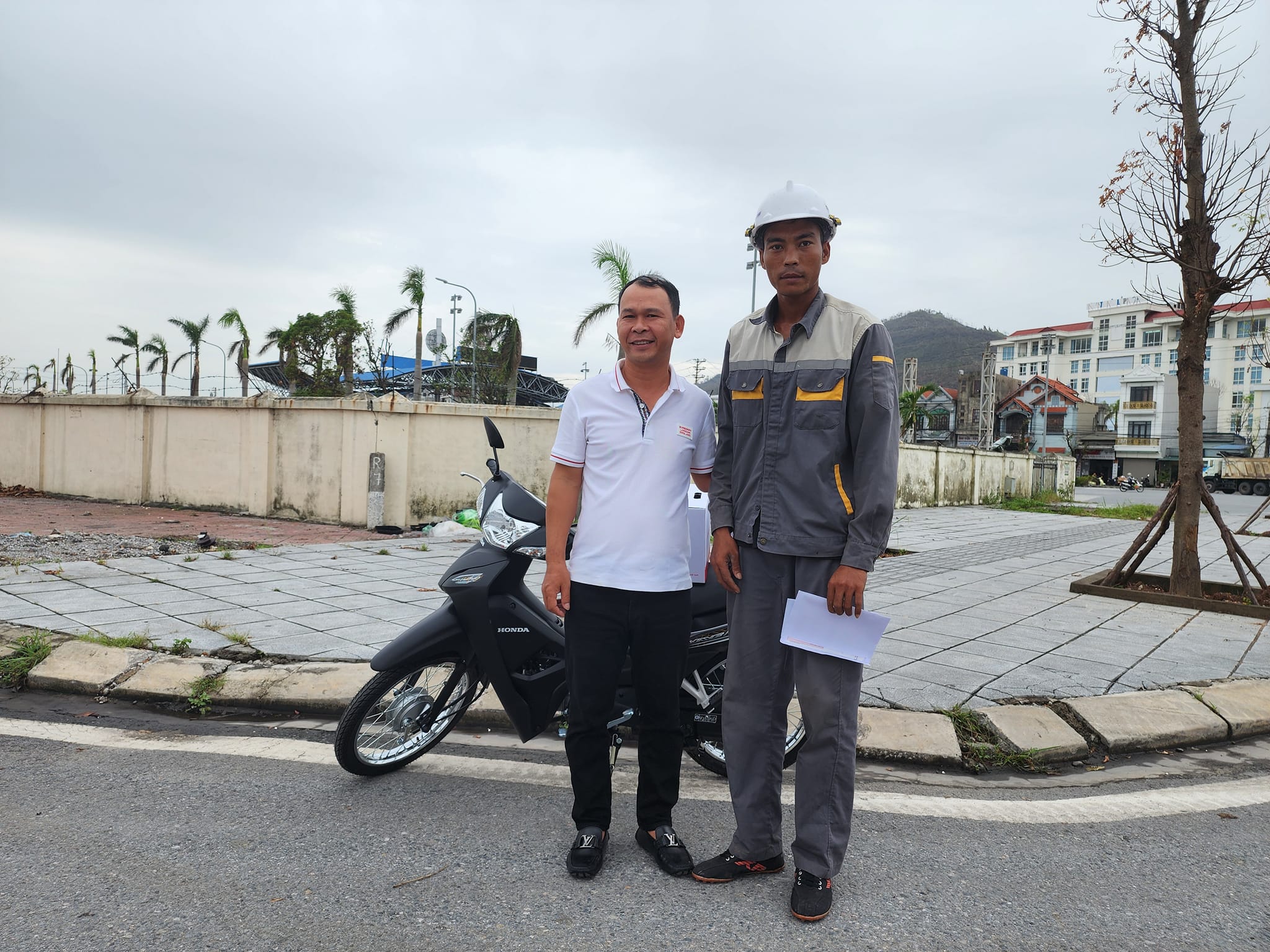 Anh Hoàng Ngô Quý (áo xám) nhận chiếc xe máy mới từ anh Lê Văn Quân (áo trắng) tại thành phố Cẩm Phả, tỉnh Quảng Ninh, sáng 23/9. Ảnh: Người Quảng Ninh