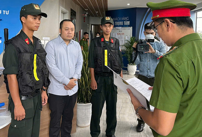 e1c94479d8b263ec3aa3-173194097-7470-7437-1731943728 Nguyễn Quang Hoàng nghe đọc lệnh khám xét nơi ở, ngày 8/11. Ảnh: Công an cung cấp