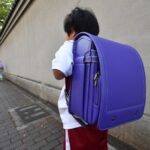 Một học sinh lớp 1 ở Kobe đang đeo chiếc balô chứa toàn bộ sách vở, vật dụng, đồ dùng học tập nặng hơn 6 kg, trên đường về nhà hôm 18/4. Ảnh: Mainichi