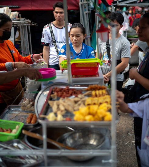 Người dân mua đồ tại một quầy hàng rong ở Bangkok (Thái Lan). Ảnh: Reuters