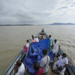 Đội y tế căng bạt và đỡ đẻ cho Jahanara Khatoon trên chiếc thuyền giữa dòng lũ sông Brahmaputra, bang Assam, đông bắc Ấn Độ ngày 3/7. Ảnh: AP