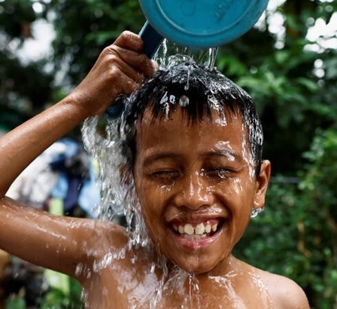 Một bé trai đổ nước lên đầu để giải nhiệt ở khu vực đông dân ở Jakarta hôm 16/5/2024. Ảnh: Willy Kurniawan/Reuters