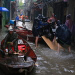 Nước ngập hết con ngõ 29 Phúc Tân, phường Phúc Tân, quận Hoàn Kiếm khiến nhiều hộ gia đình buộc phải thuê thuyền hoặc lội nước để đưa người và xe máy đến nơi an toàn, chiều 11/9. Ảnh: Thanh Nga